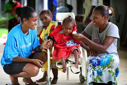 Volunteer supporting a child with mobility needs